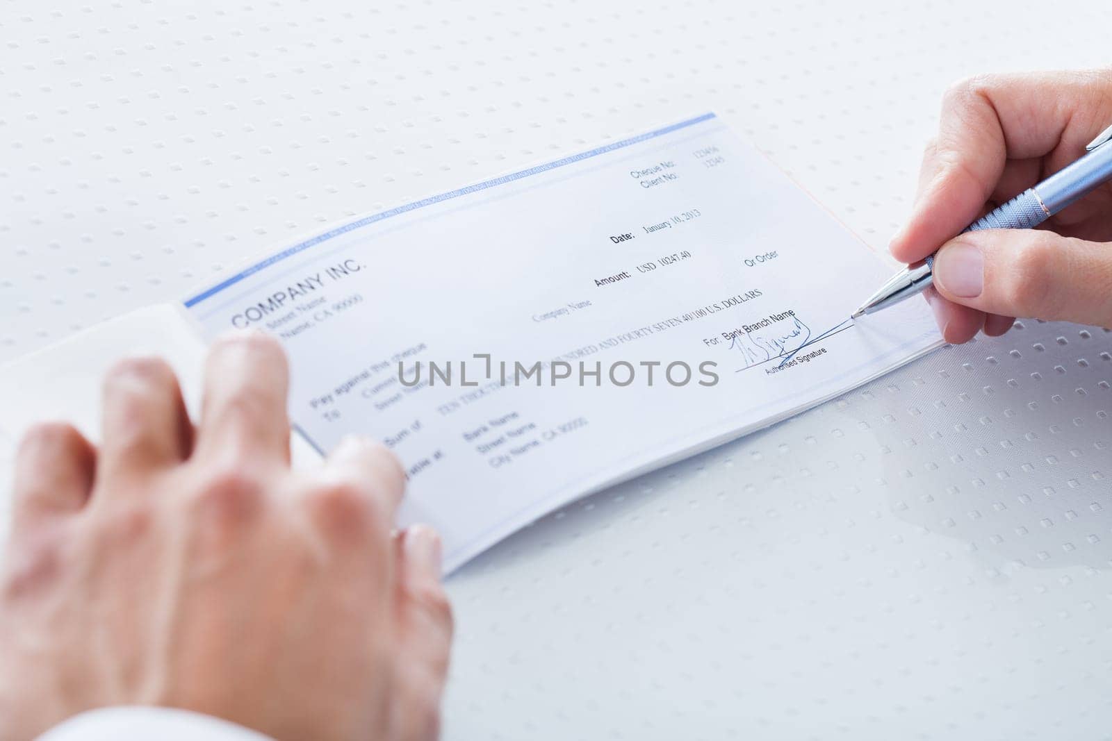 A Male Hand Filling Out The Amount On A Cheque
