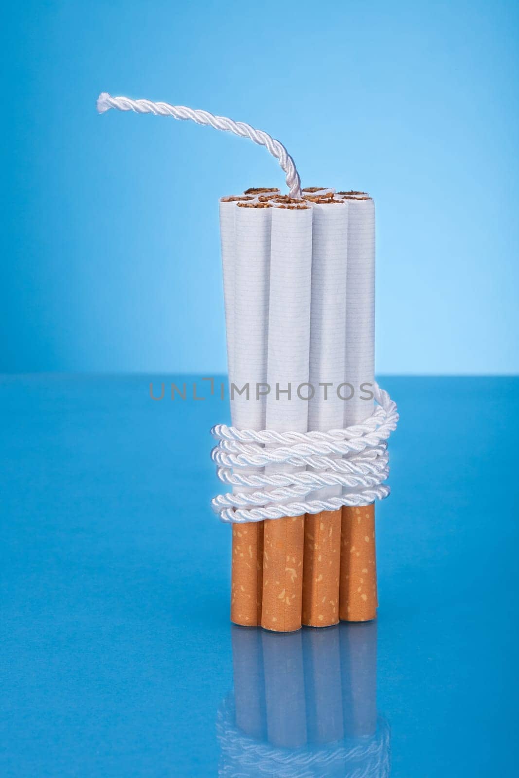 Cigarettes Tied With Rope And Wick Over Blue Background