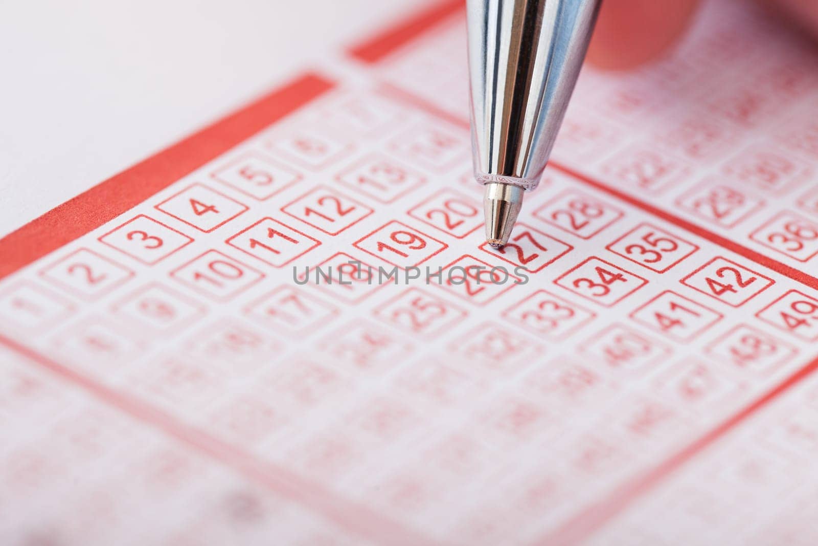 Close-up Of A Person Marking Number On Lottery Ticket With Pen