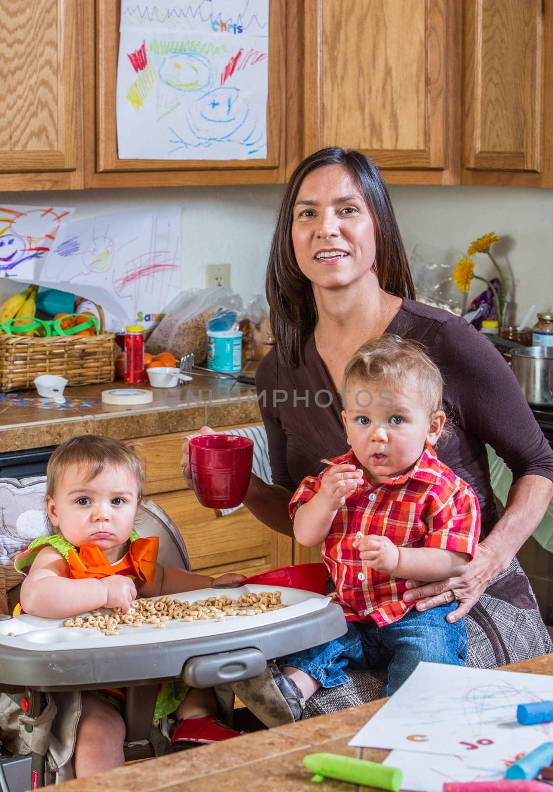 A mother in the kitchen poses with babies