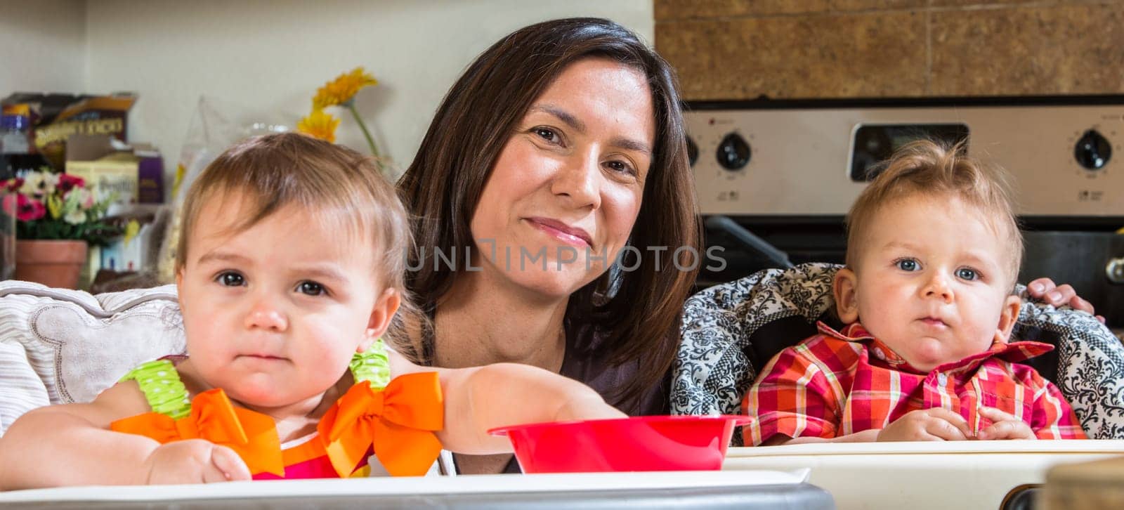A mother in the kitchen poses with babies