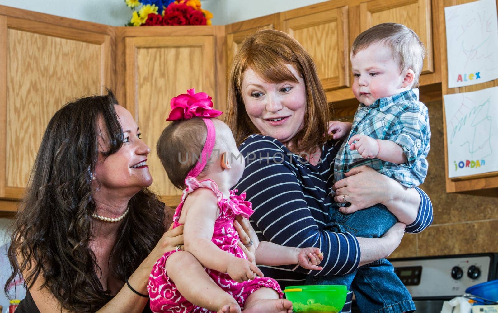 Mothers in kitchen play with their babies