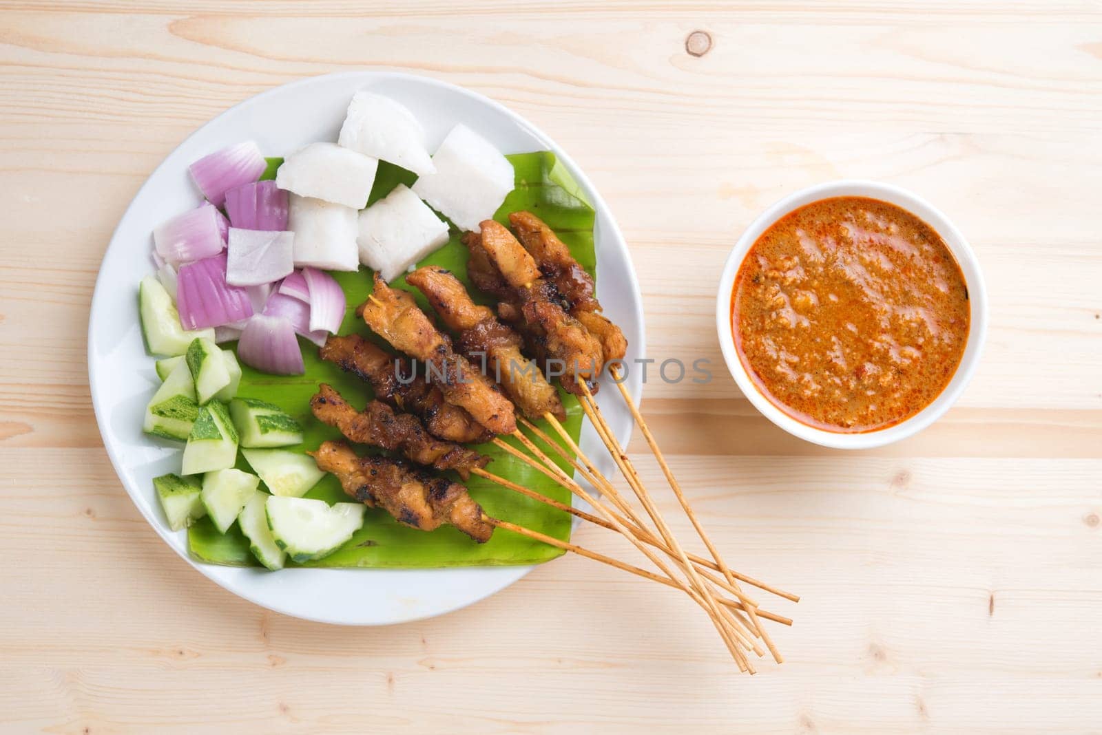 Overhead view delicious chicken satay on wooden dining table, one of famous Malaysian local dishes.