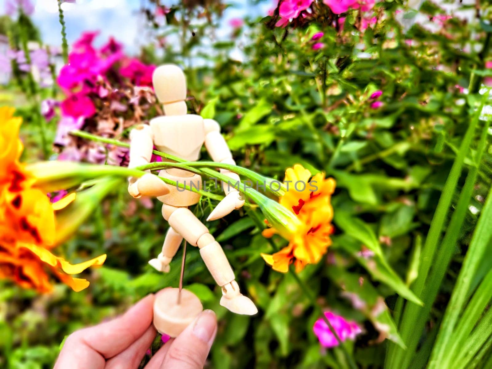 Wooden toy man with flowers in hand of woman and background grass. Concept of holiday, gift bouquet, Valentine's Day, proposal, engagement, declaration of love, Mother's Day. Caring, loving, romantic by keleny