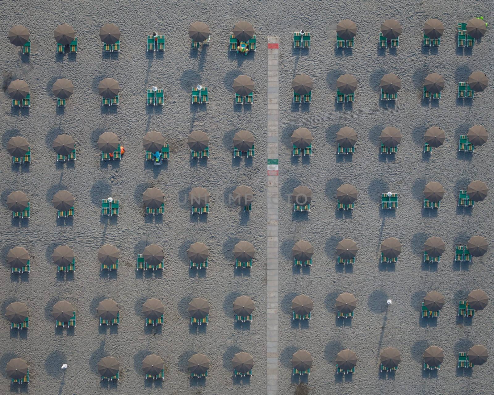 Aerial view of large group of tidy beach umbrellas, beach parasol shot from above,Italy.