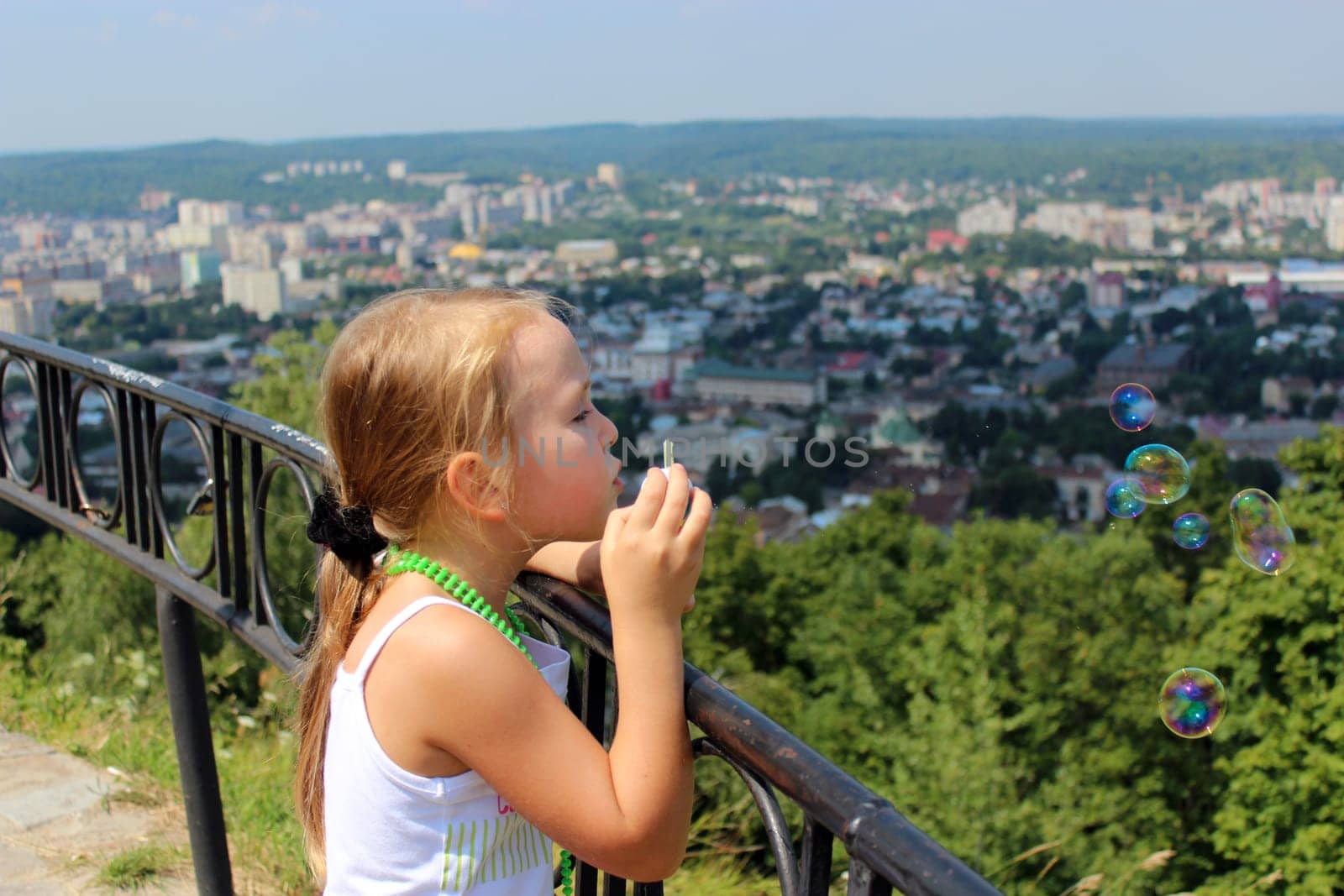 little girl swelling soap big bubbles out of city