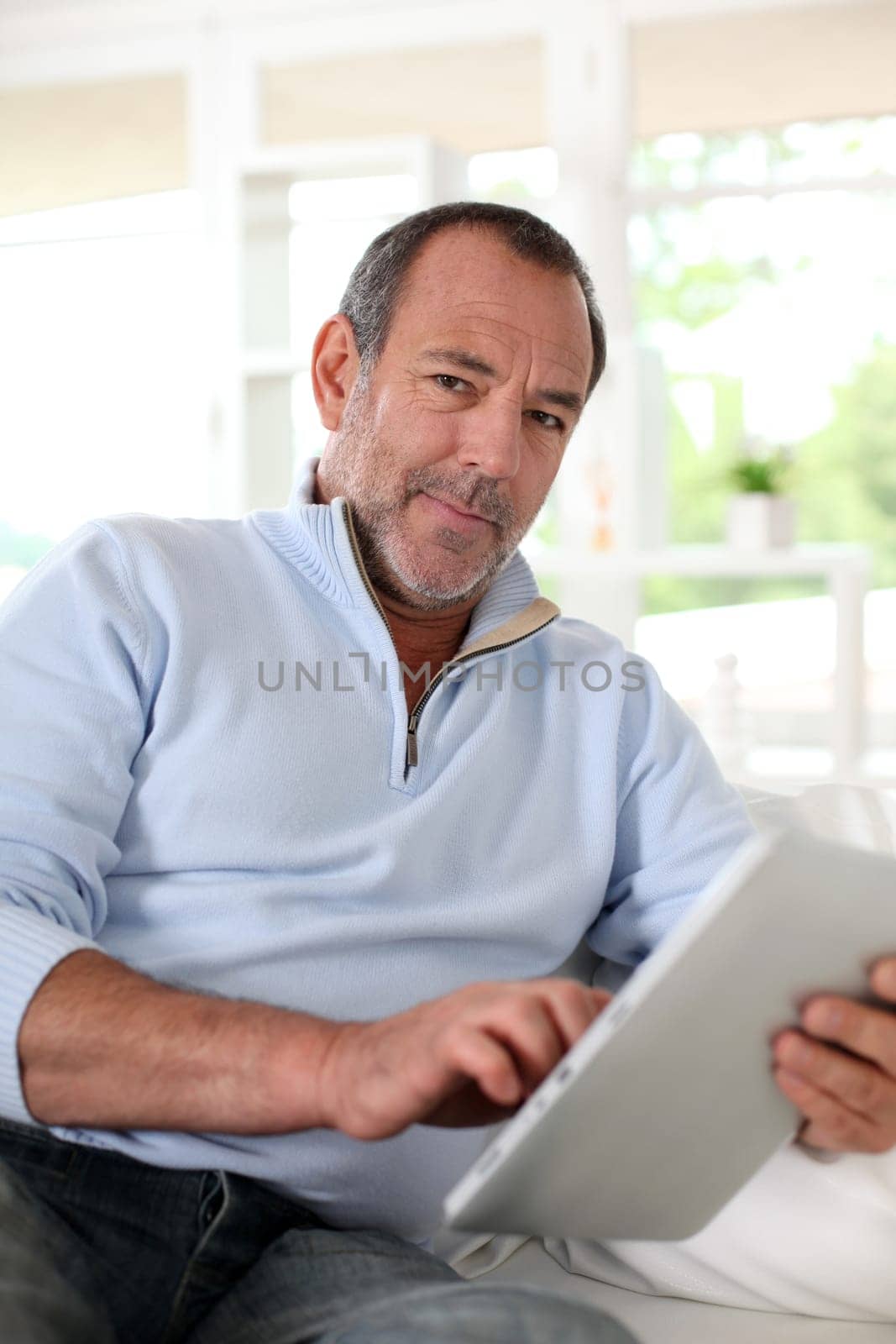 Senior man at home using electronic tablet