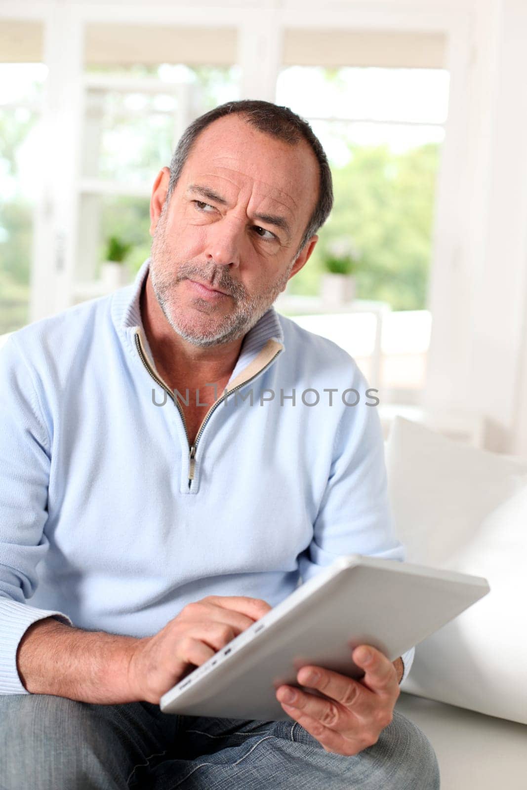 Senior man at home using electronic tablet