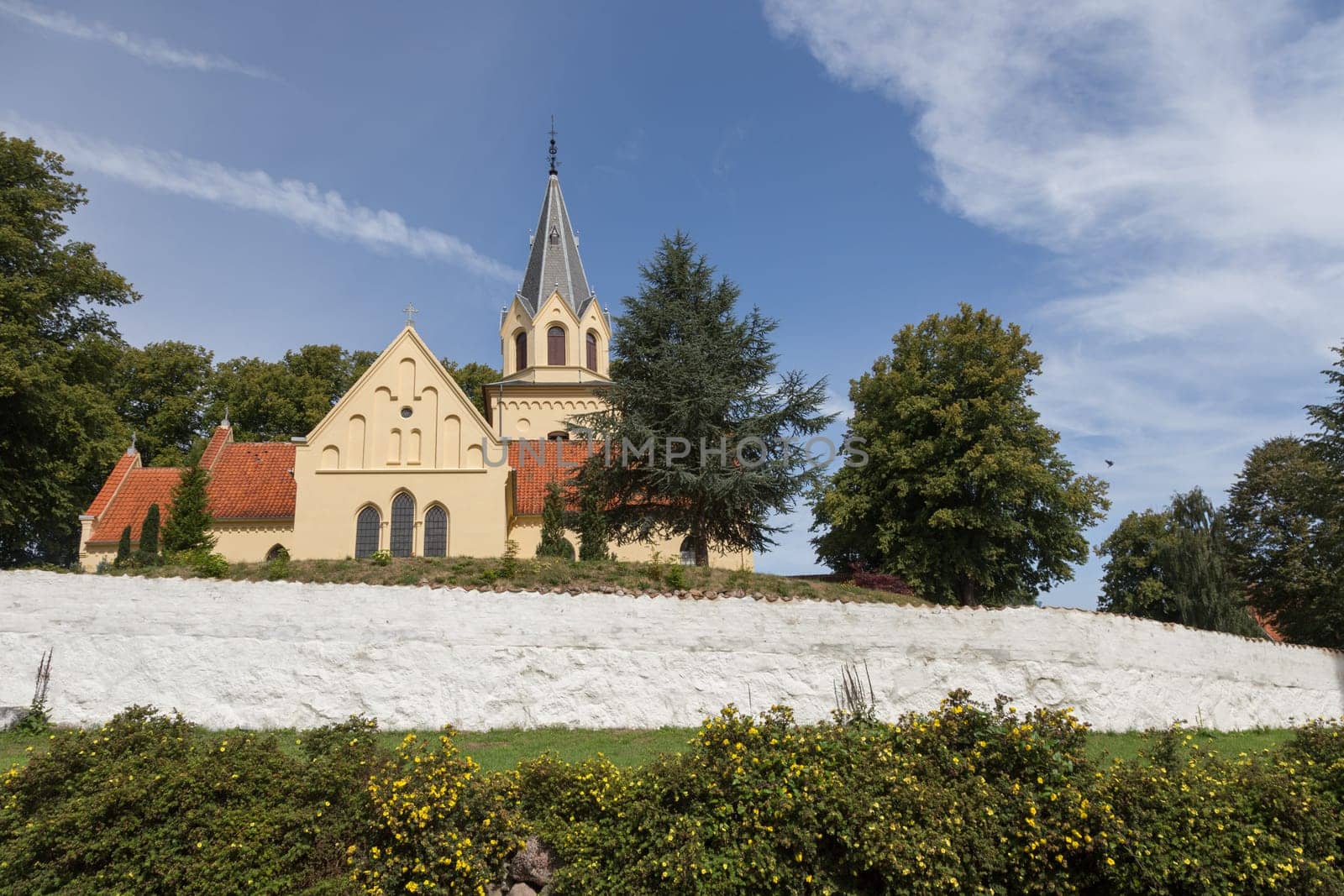 Yellow church behind white cemetery wall