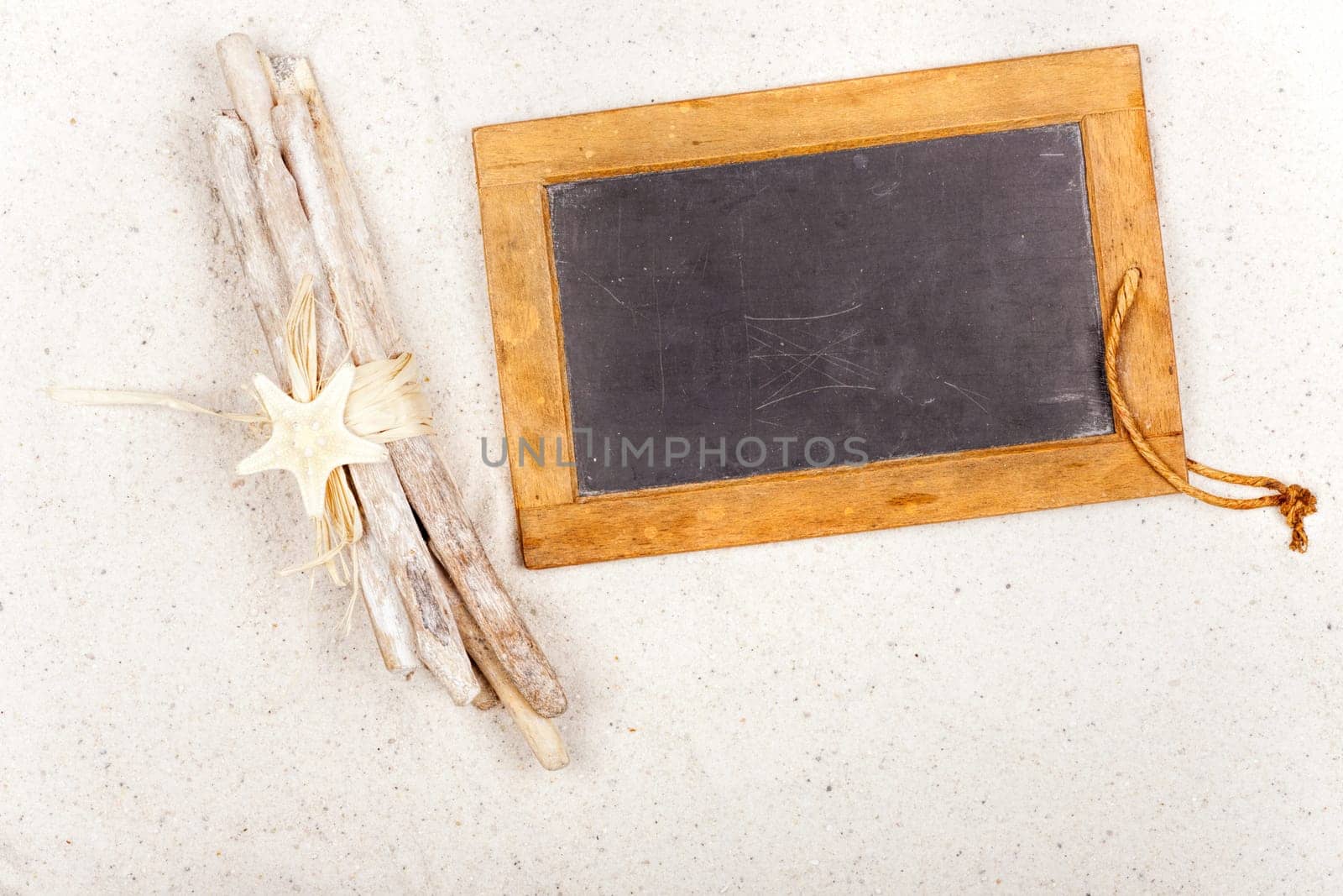 Empty slate board with decoration in the sand