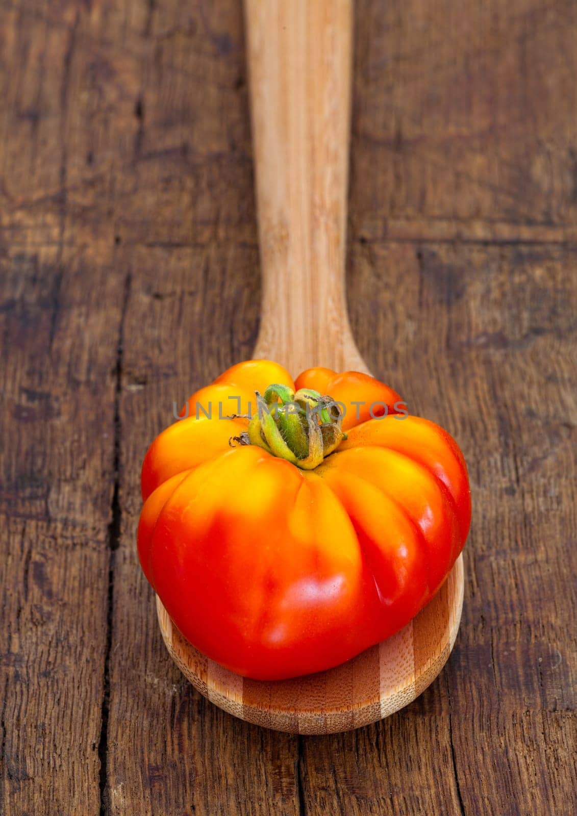 Mature meat tomato lies on a wooden spoon