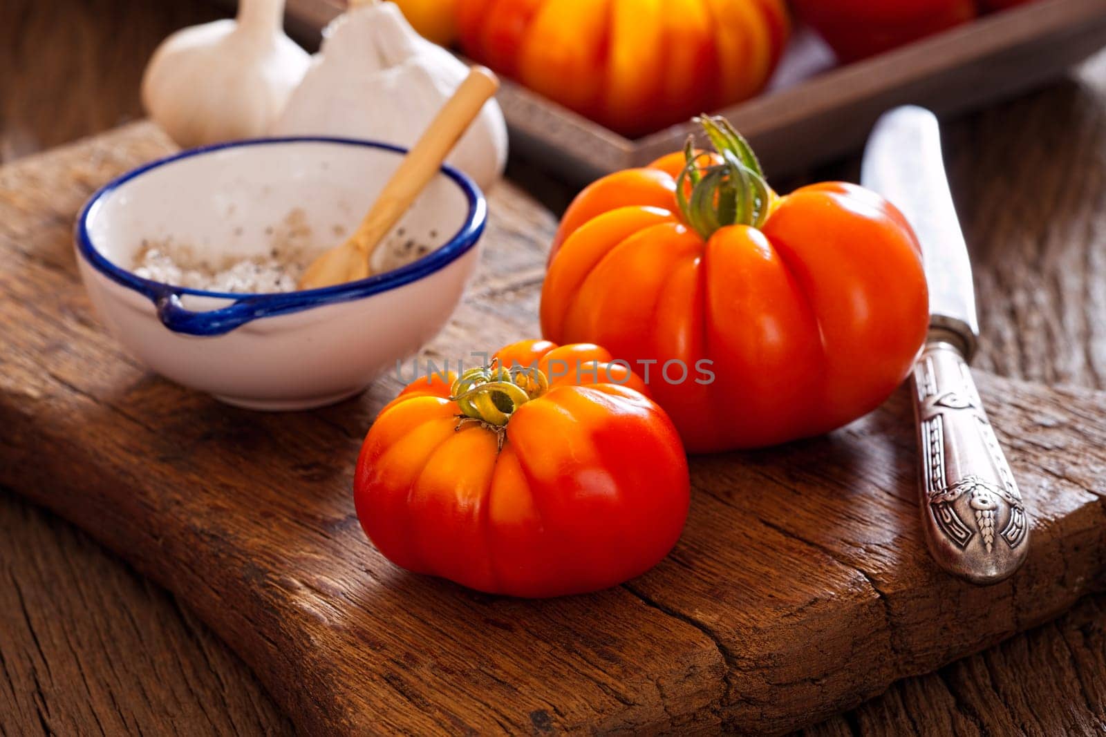 Meat tomatoes with knife and salt on cutting board