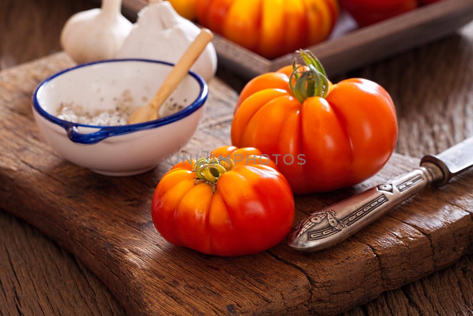 Meat tomatoes with knife and salt on cutting board