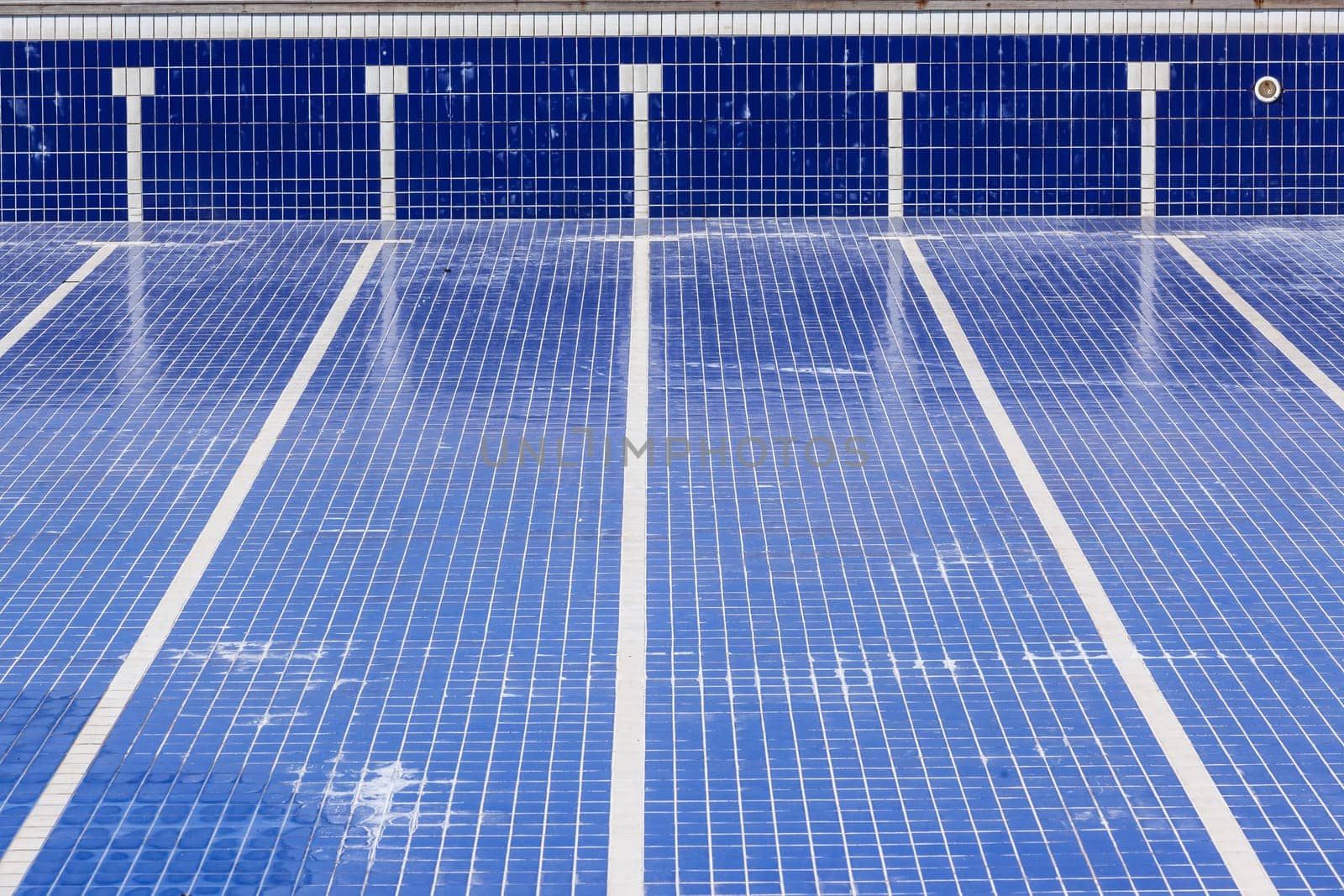 Swimming pool with blue ties and swim lane tile markings empty of water for maintenance