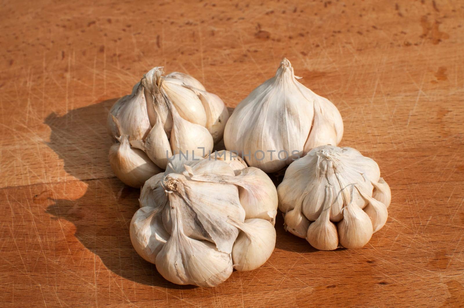 Four garlic cloves on wooden board background