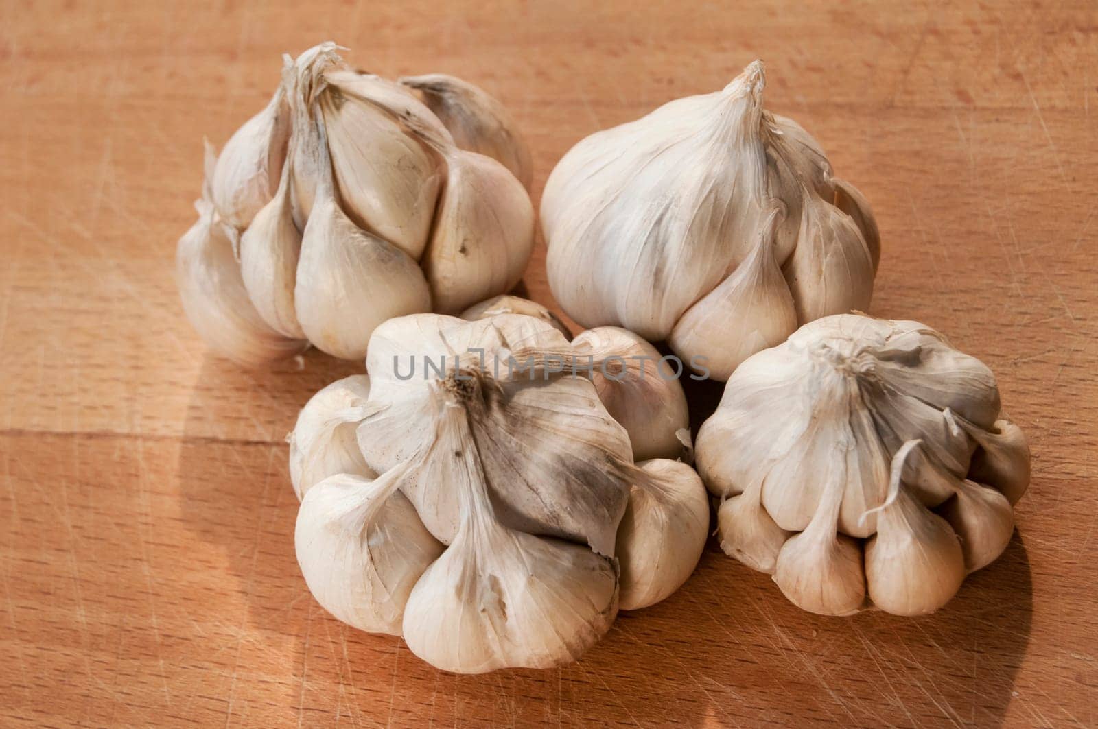 Four garlic cloves on wooden board background