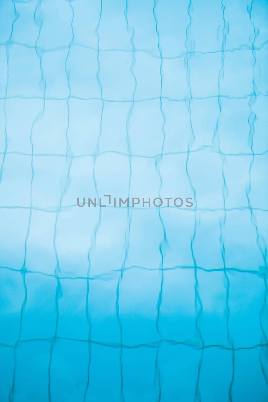 Tiles on bottom of swimming pool distorted slightly by water for background image
