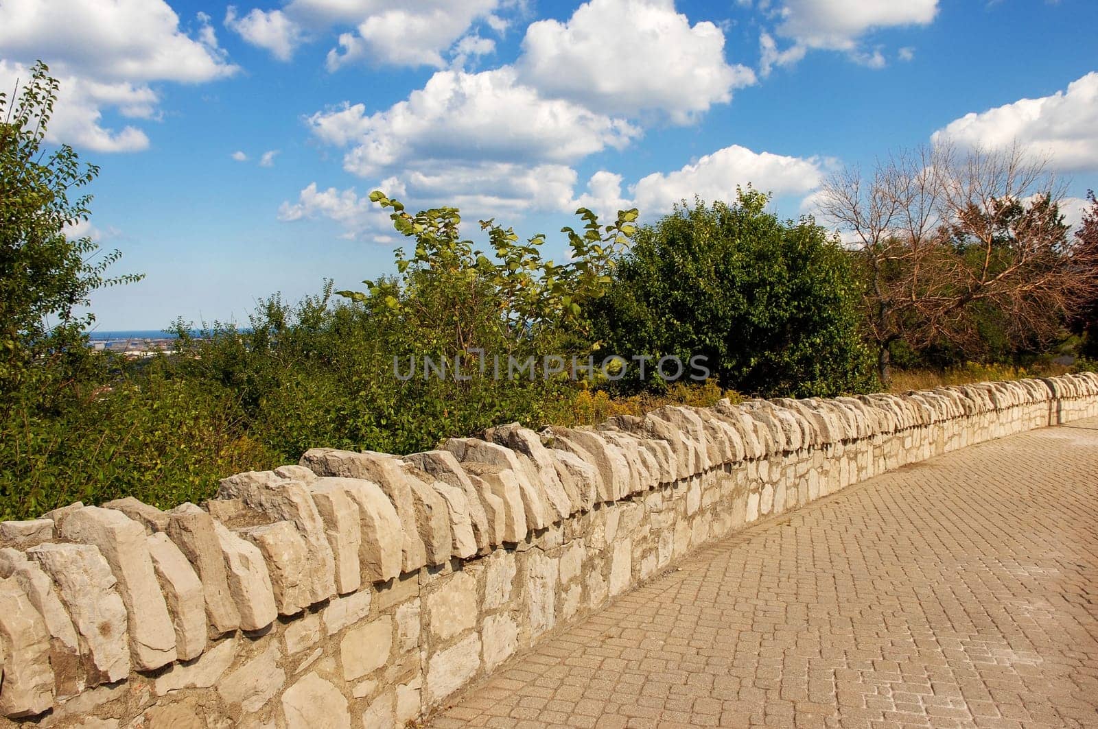 A natural old stone wall on a sidewalk in a park in Hamilton.Canada in the summer..