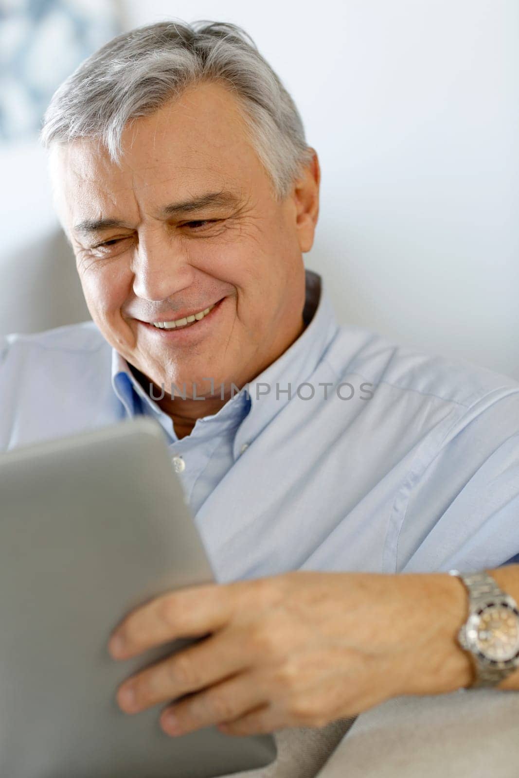 Senior man at home using electronic tablet