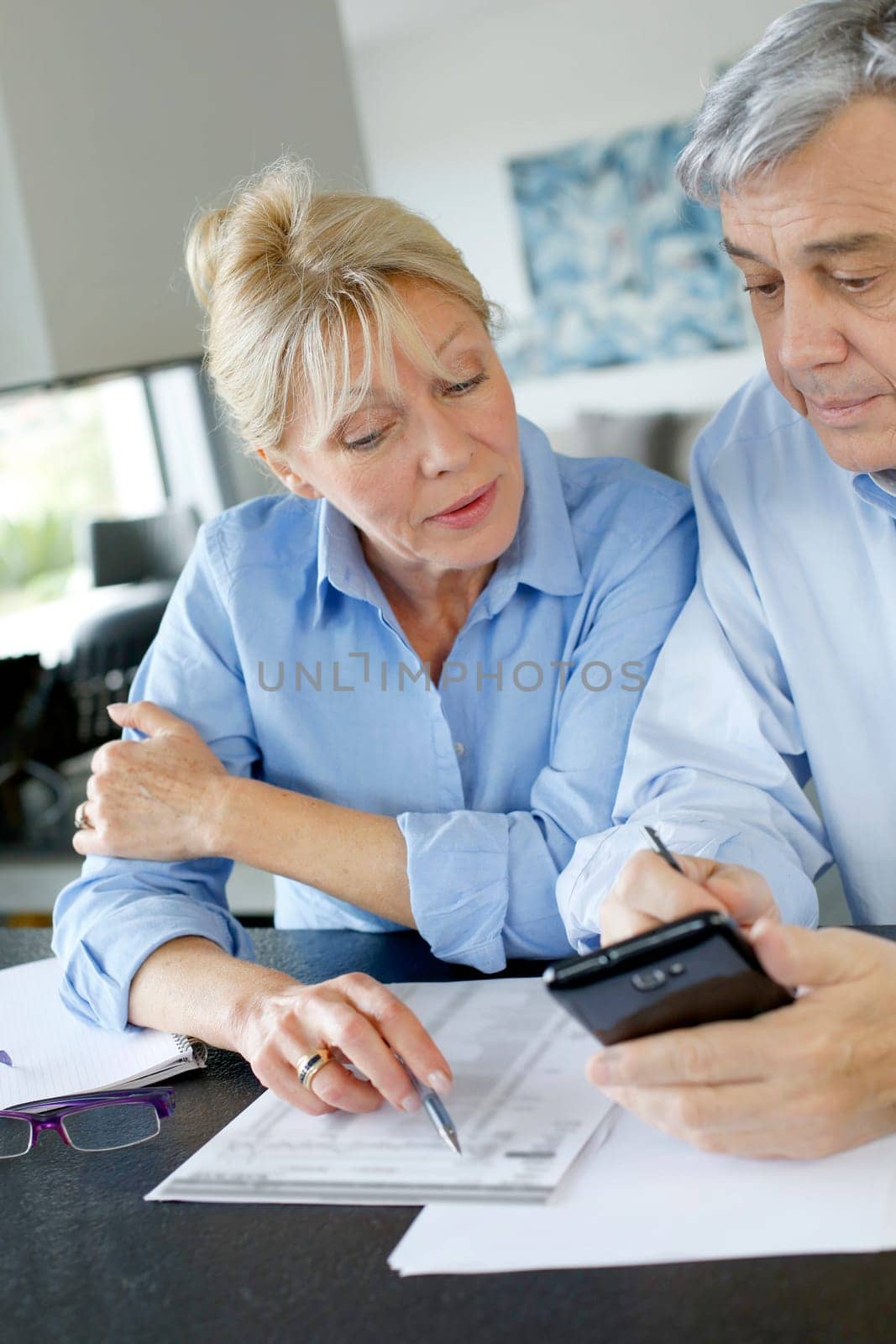 Senior couple calculting bills amount using smartphone