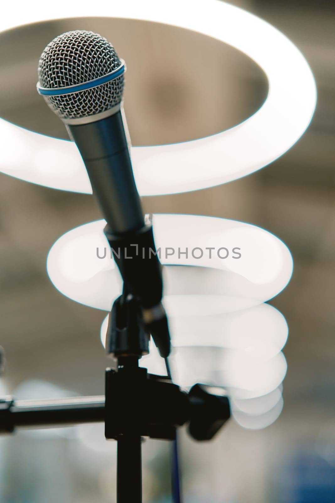 Microphone stands on the stage against the backdrop of glowing lamps by Nadtochiy