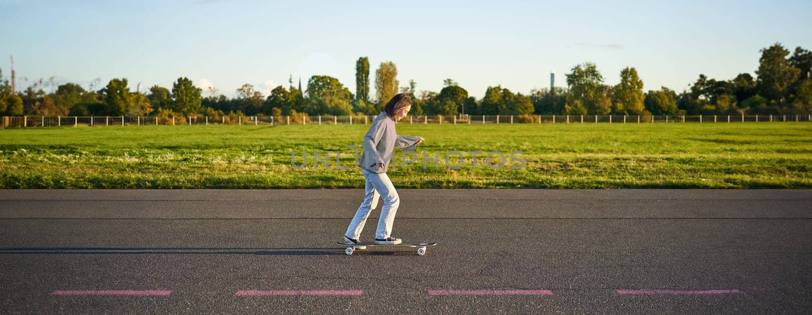Hobbies and lifestyle. Young woman riding skateboard. Skater girl enjoying cruise on longboard on sunny day outdoors.