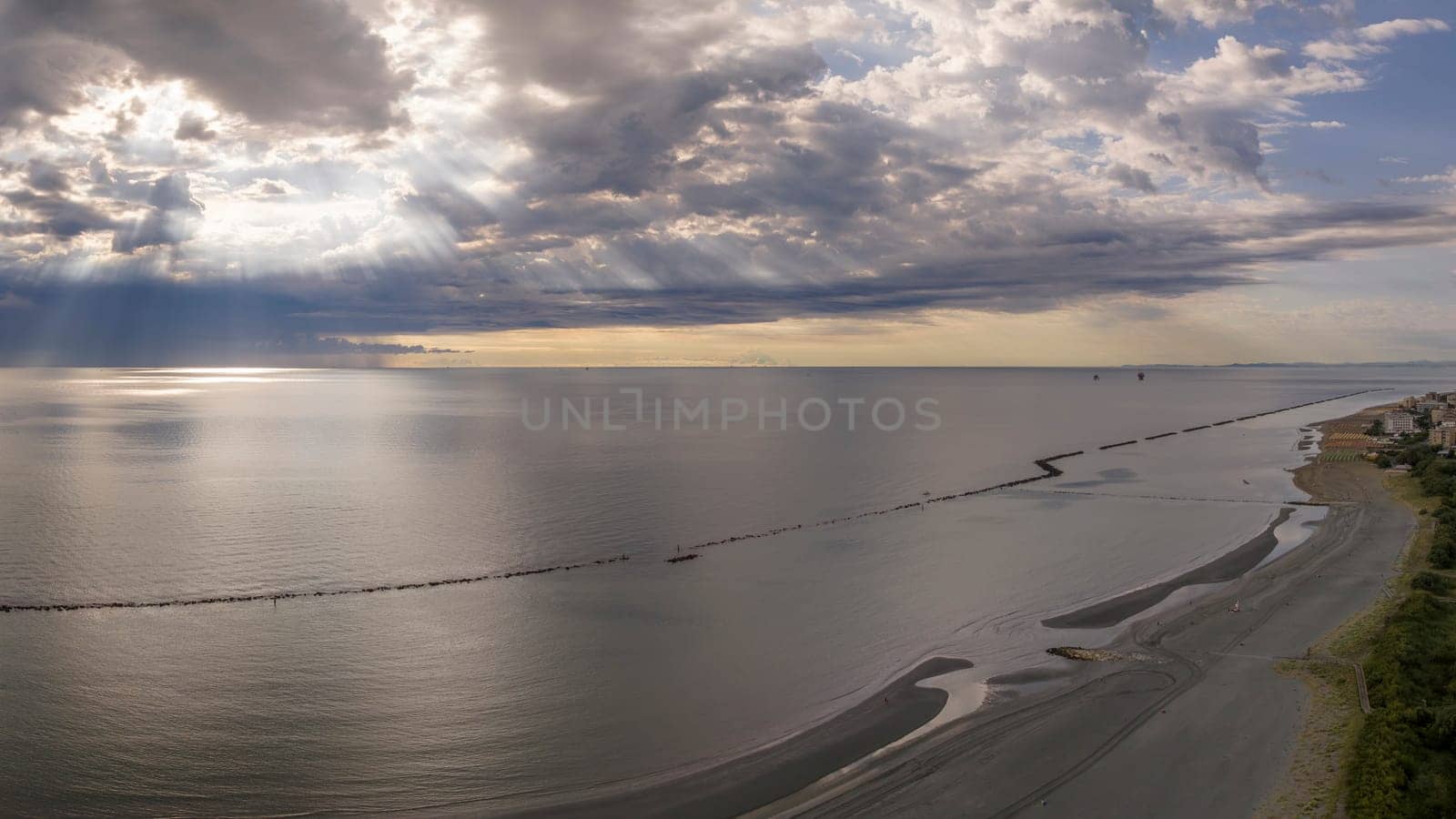 Aerial view of sandy beach and stormy sky with sun rays piercing the clouds by Robertobinetti70