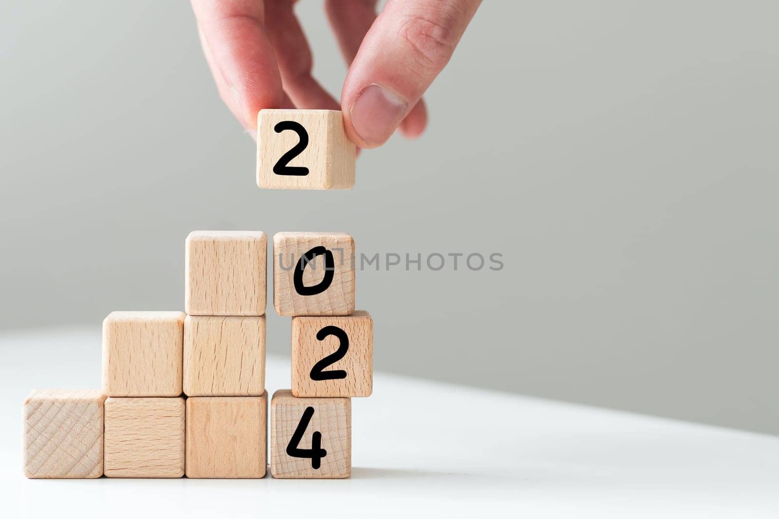 2024 in concept of wooden block numbers. Human hand holding block number isolated on white. High quality photo