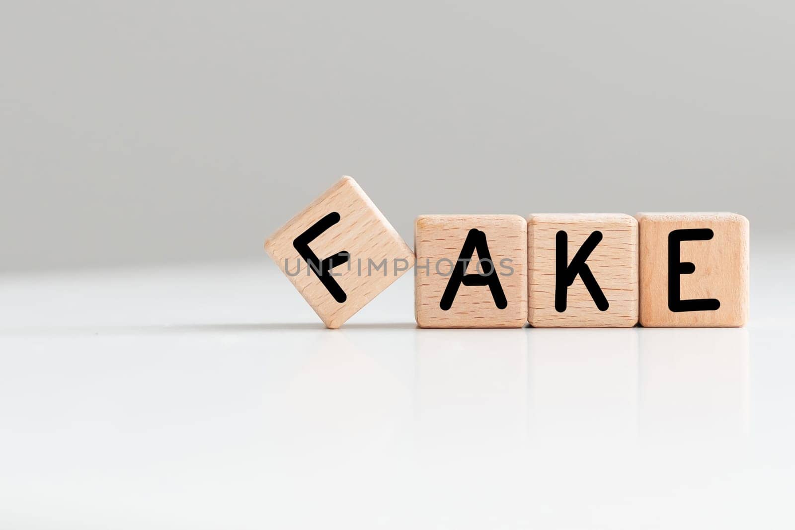 FAKE word written in wooden blocks on white background. High quality photo