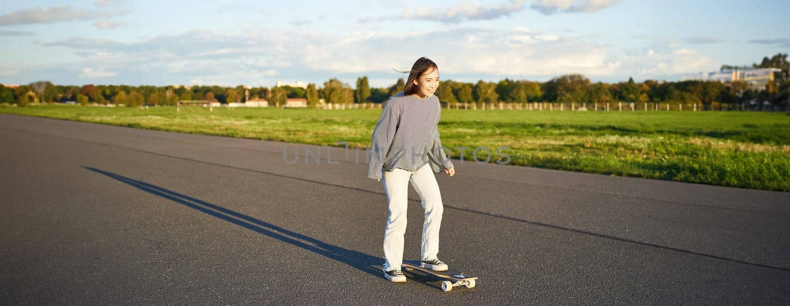 Hobbies and lifestyle. Young woman riding skateboard. Skater girl enjoying cruise on longboard on sunny day outdoors.