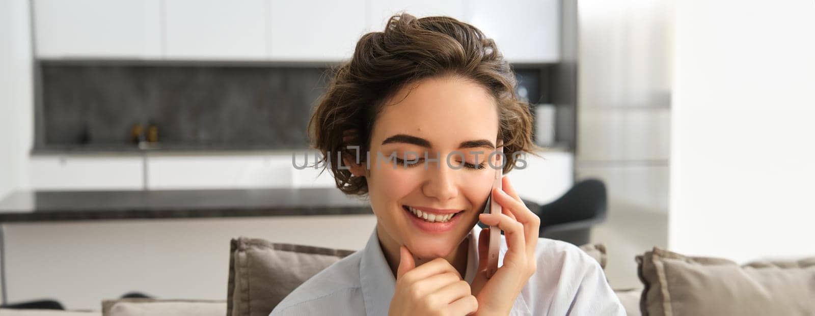 Close up portrait of smiling beautiful woman, talking on mobile phone, chats on smartphone, calls someone, sits at home.