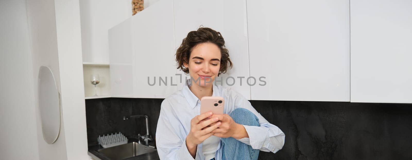 Portrait of woman sitting at home with mobile phone, online shopping on smartphone app, spending time indoors.