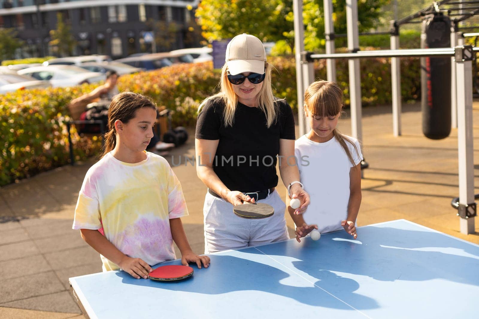 Family playing table tennis in the summer outdoors by Andelov13