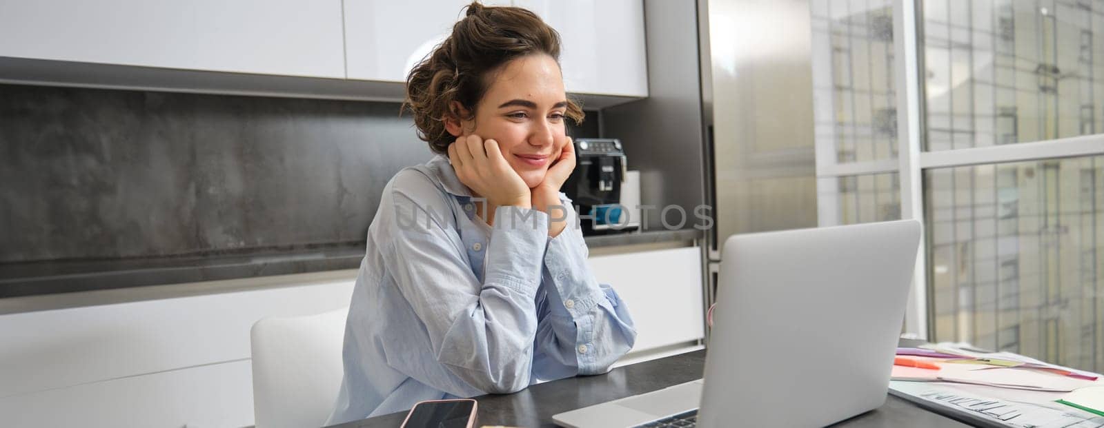 Image of smiling woman studying on remote, looking at laptop while sitting at home, watching webinar, doing online course on computer by Benzoix