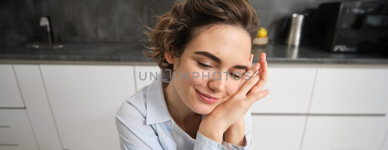 Close up portrait of young woman, 25 years old, sitting in her kitchen alone, express candid happiness, smiles, leans head on hands by Benzoix