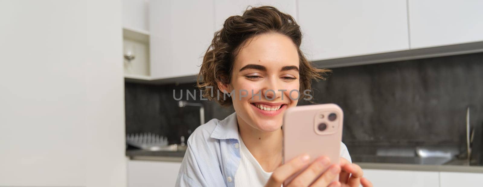 Portrait of beautiful woman at home, holding smartphone, online shopping from mobile phone app.