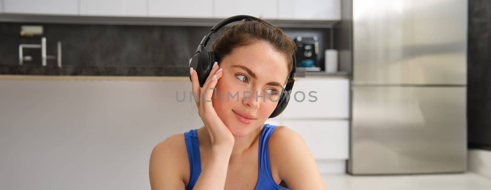 Close up portrait of fitness woman, wearing sportsbra, listening music in headphones, working out at home, doing exercises for fit and healthy body by Benzoix