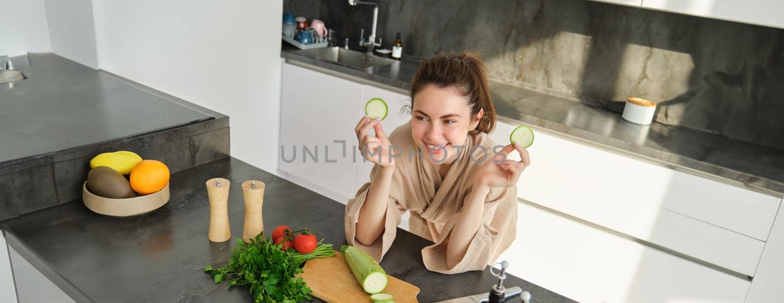Portrait of beautiful brunette girl chopping vegetables for meal, making salad in the kitchen, eating healthy food, preparing dinner.