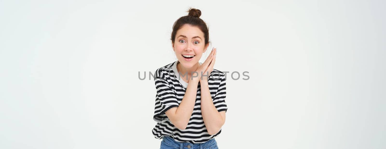 Portrait of amazed young woman, claps hands and gazing at something beautiful, isolated over white background. Copy space