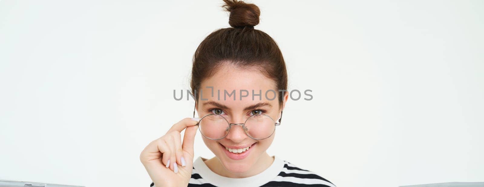 Close up portrait of smiling, beautiful young woman, student in glasses, looking at camera with confidence and laughing, white background.