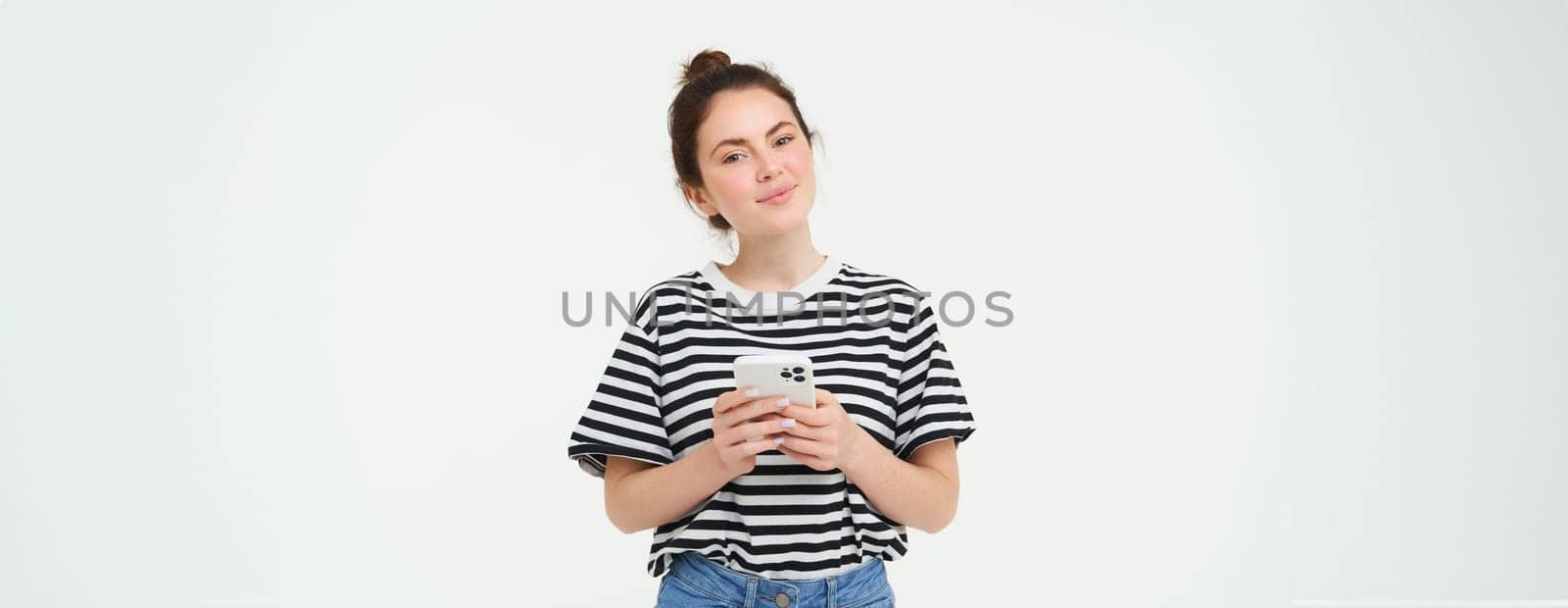 Image of young smiling woman, holding mobile phone, using smartphone application, isolated over white background by Benzoix