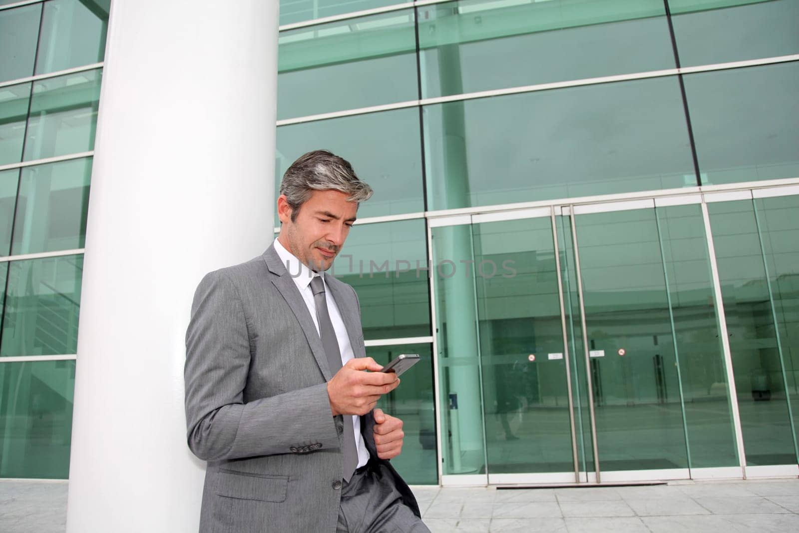 Businessman writing short message on mobile phone