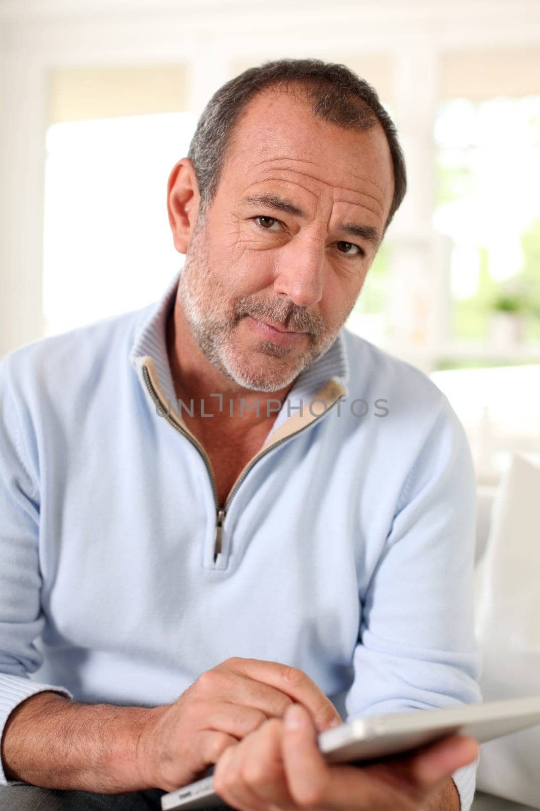 Senior man at home using electronic tablet