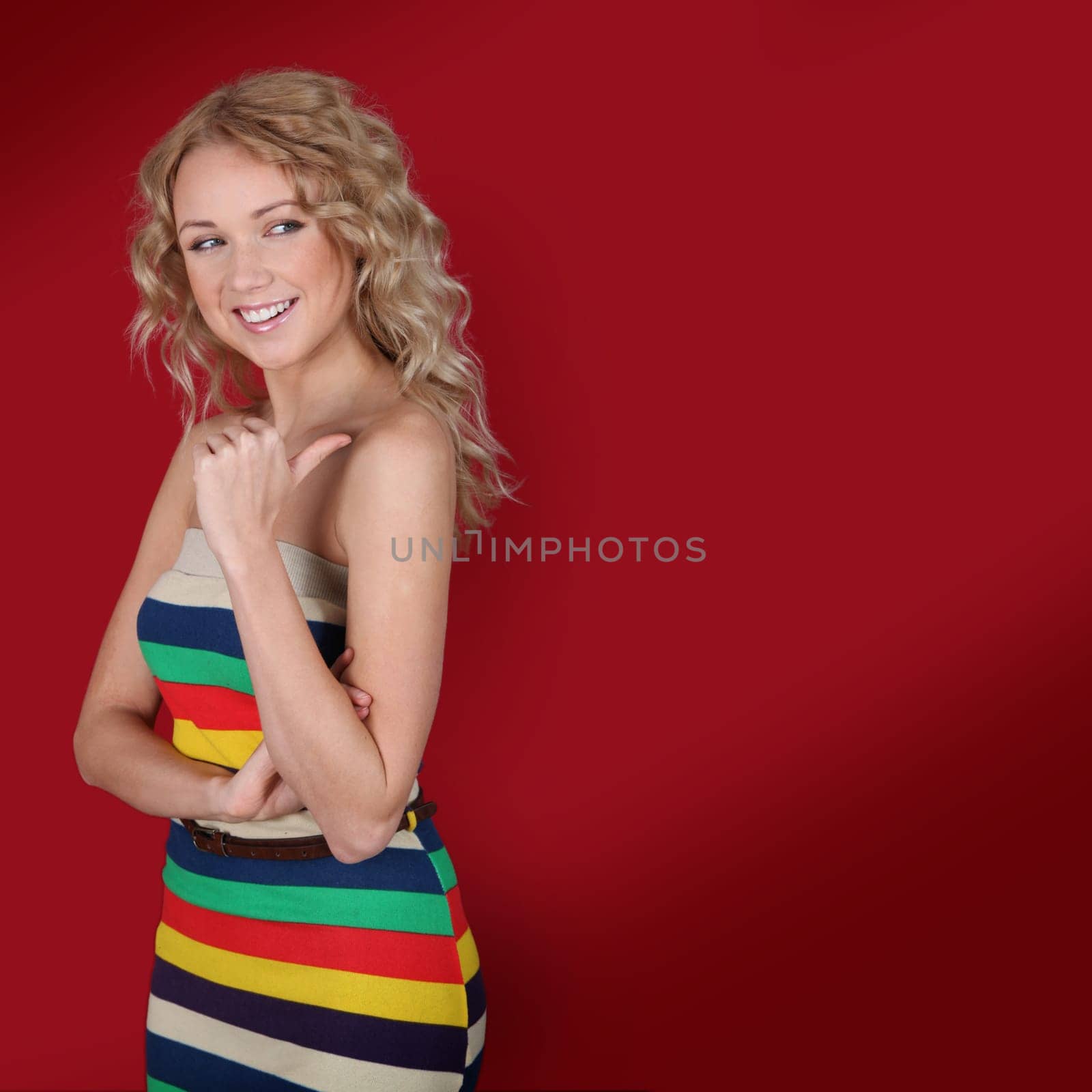 Beautiful blond woman showing thumb up on red background