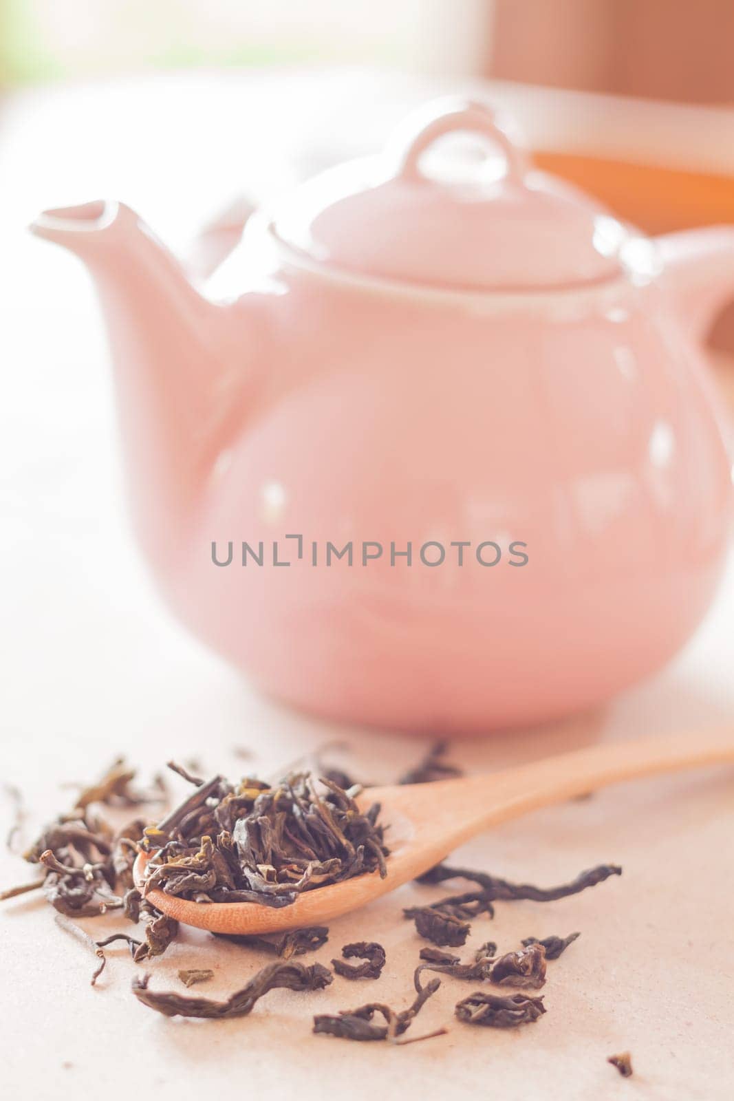 Dry tea in wooden spoon with ceramic jar, stock photo