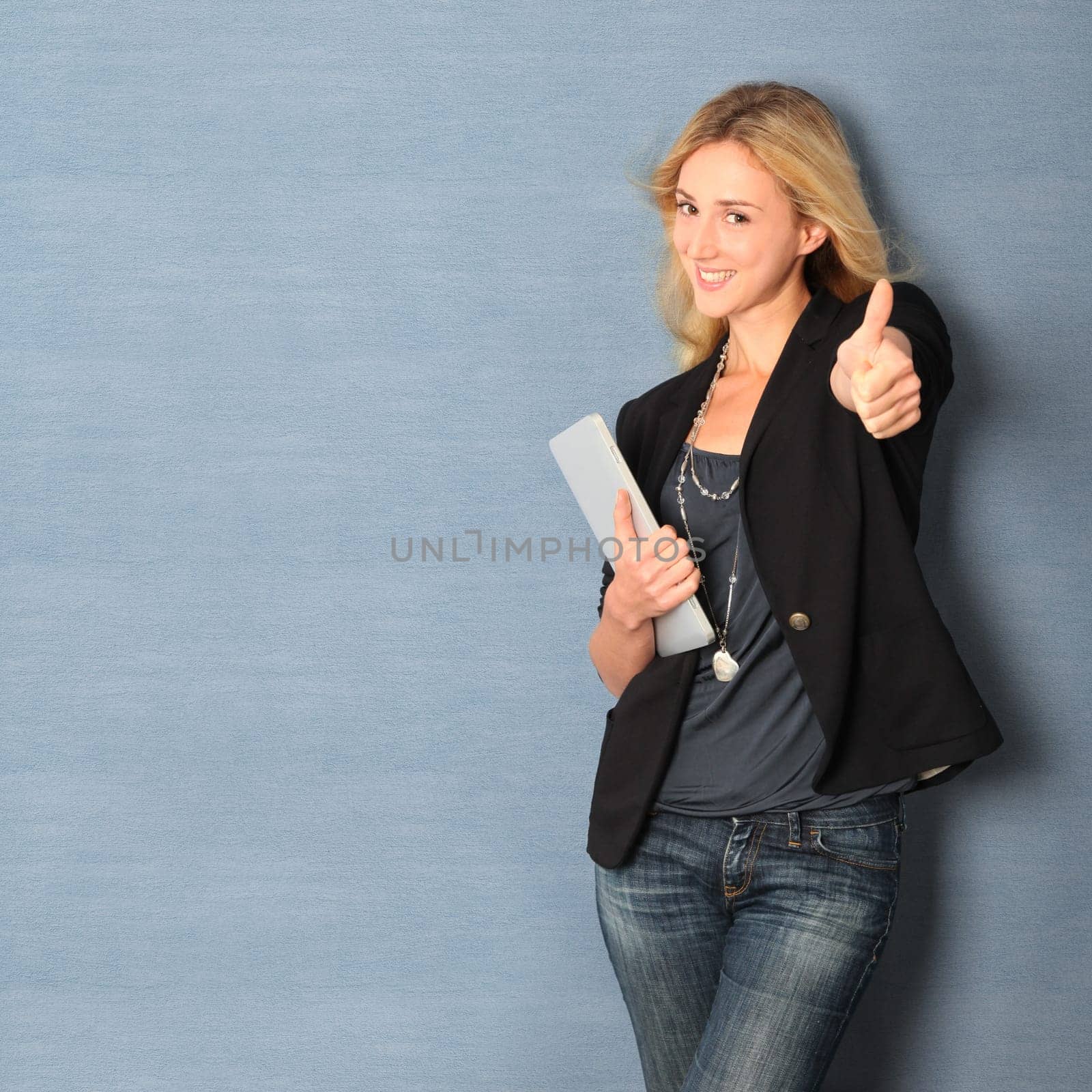 Beautiful woman leaning on wall with touchpad