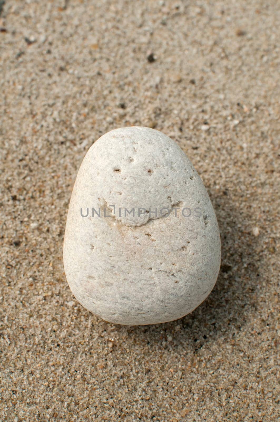 Naturally received image of smile on sea pebble stone on sand background