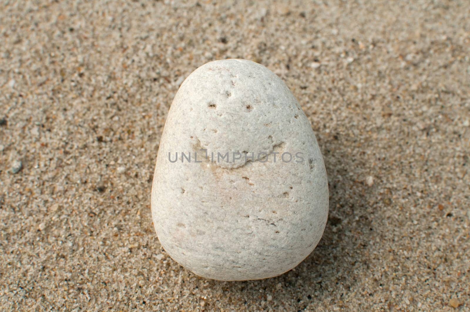 Naturally received image of smile on sea pebble stone on sand background