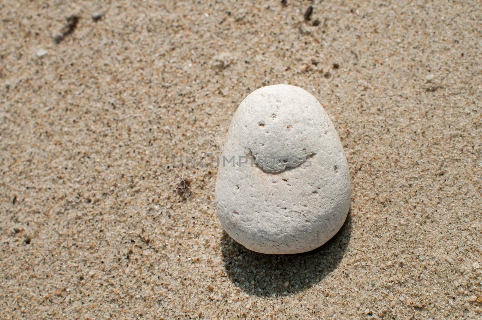Naturally received image of smile on sea pebble stone on sand background