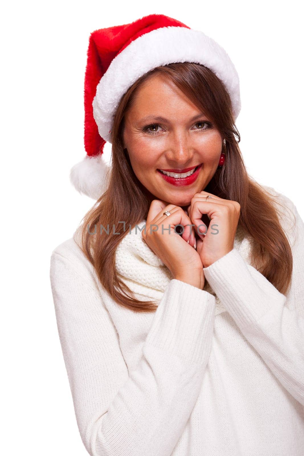 Attractive woman wears a festive red Christmas hat and cuddles up in a turtleneck sweater with a charming friendly smile,isolated on white